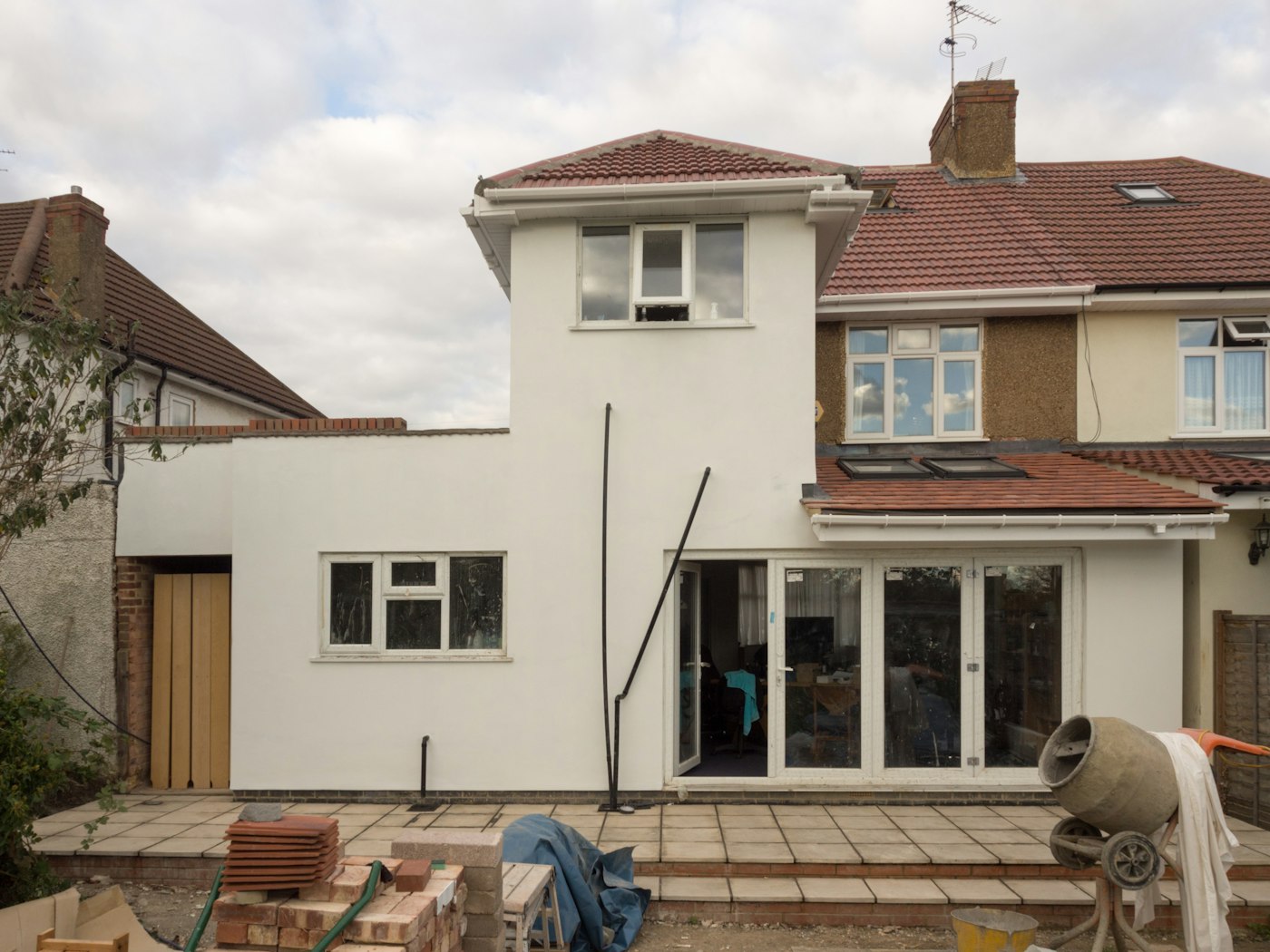 Single-family house mid-renovation with new siding going up along one elevation