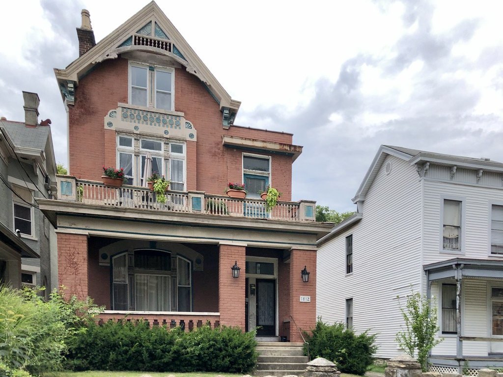 Well-kept brick multi-family house with a covered porch on a residential street