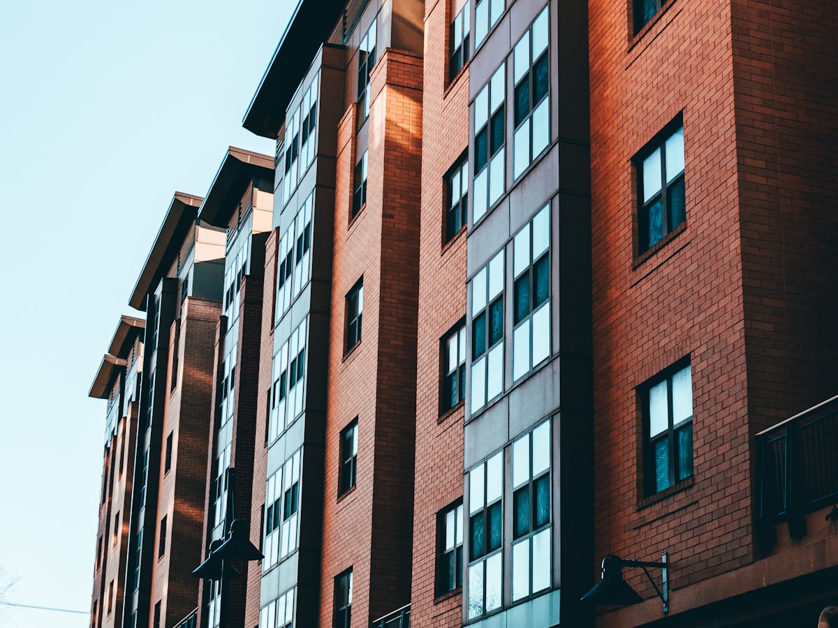 A row of small multifamily brick apartment buildings under a clear sky